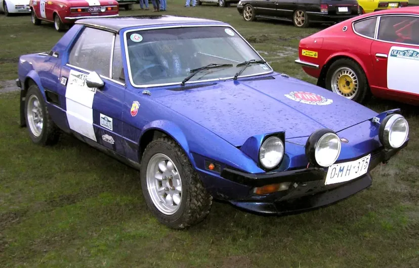 A yellow Fiat X1/9 passing bunting and a marker cone at the Ye Olde BP Rally.